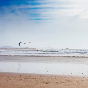 A sunny view of the Atlantic Ocean from a beach in Essaouira Morocco with people kite surfing in the distance